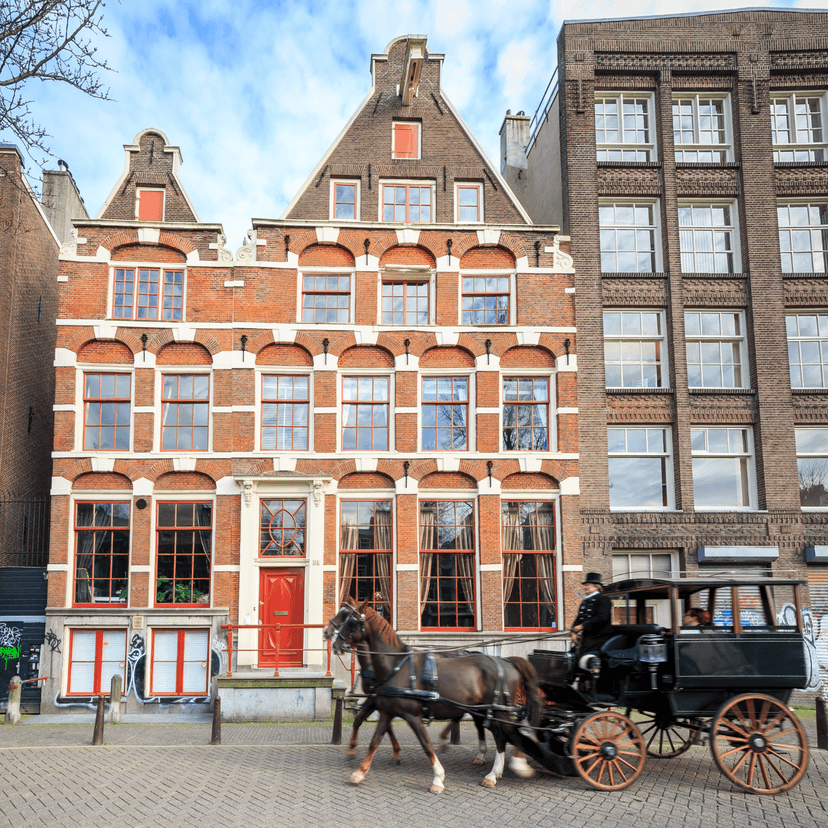 Foto van grachtenpand met koets op de voorgrond