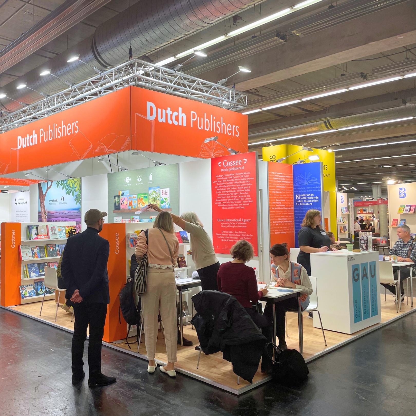 Mensen staan en zitten bij Nederlandse stand op de boekenbeurs