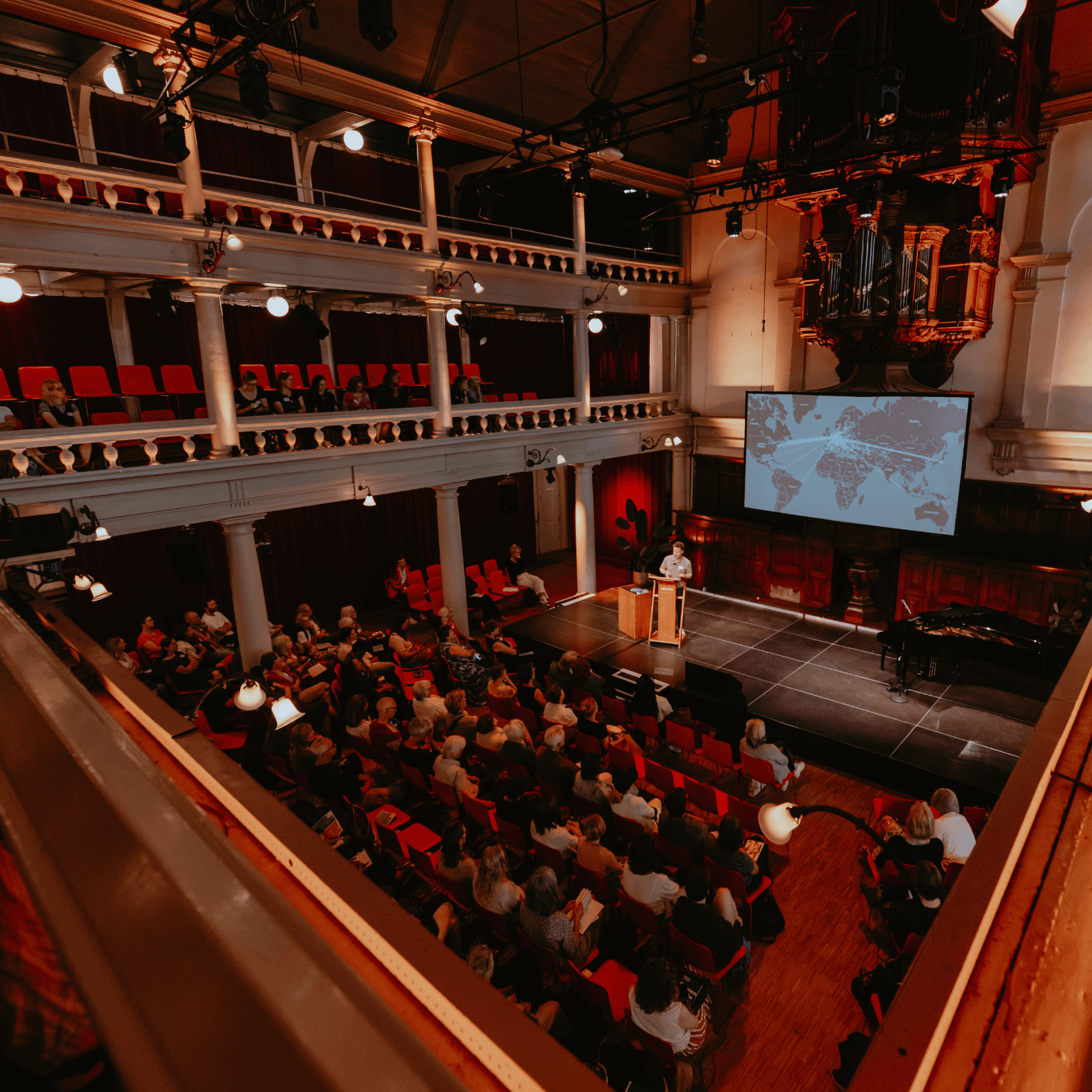Zaal met publiek en spreker op podium